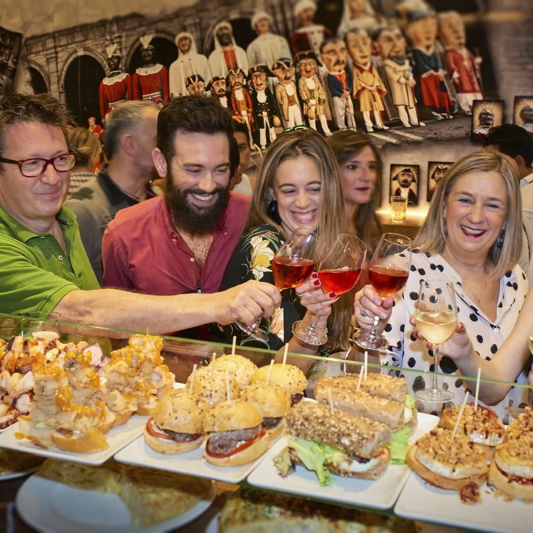 Amigos brindando junto a una barra repleta de pinchos